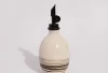 Squat Oil Pourer in Zebra: round cream stoneware oil bottle with dark marbled stripes and a black pour spout