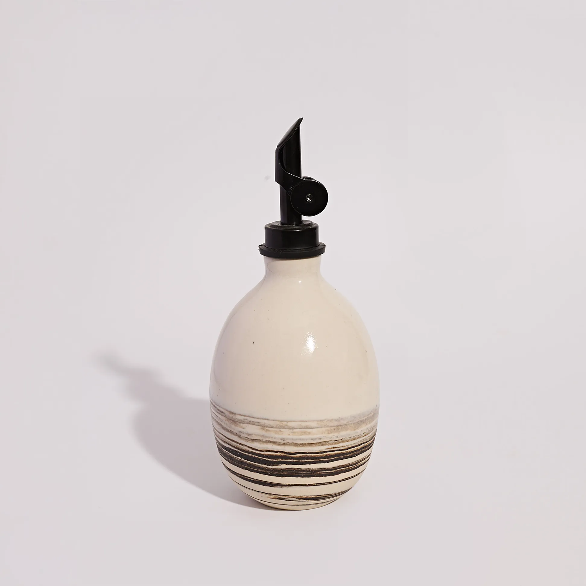 Squat Oil Pourer in Zebra: round cream stoneware oil bottle with dark marbled stripes and a black pour spout